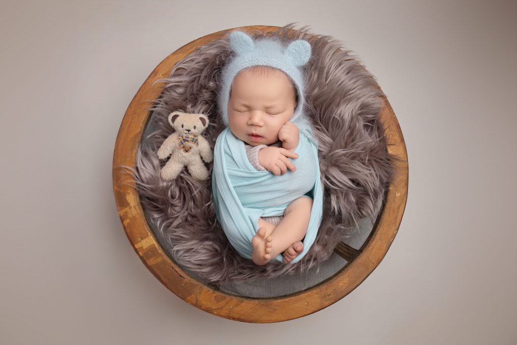Swaddled newborn baby boy with teddy bonnet